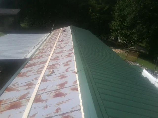 Old rusted panels beside newly installed green metal roofing — Wind Damage Roof Repair by Roofing Brothers in Fort Calhoun
