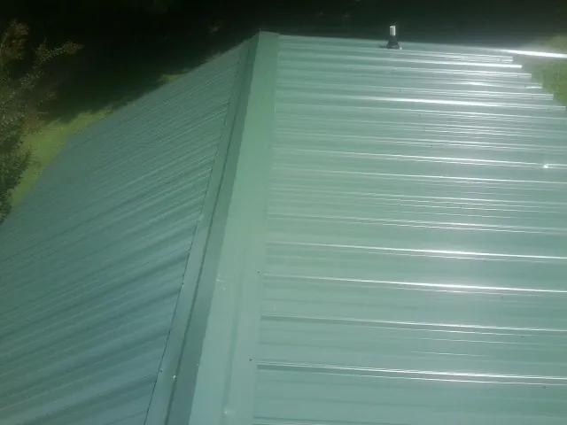 New green metal panels meeting at the ridge of a roof — Flat Roof Repair work by our crew in Fort Calhoun