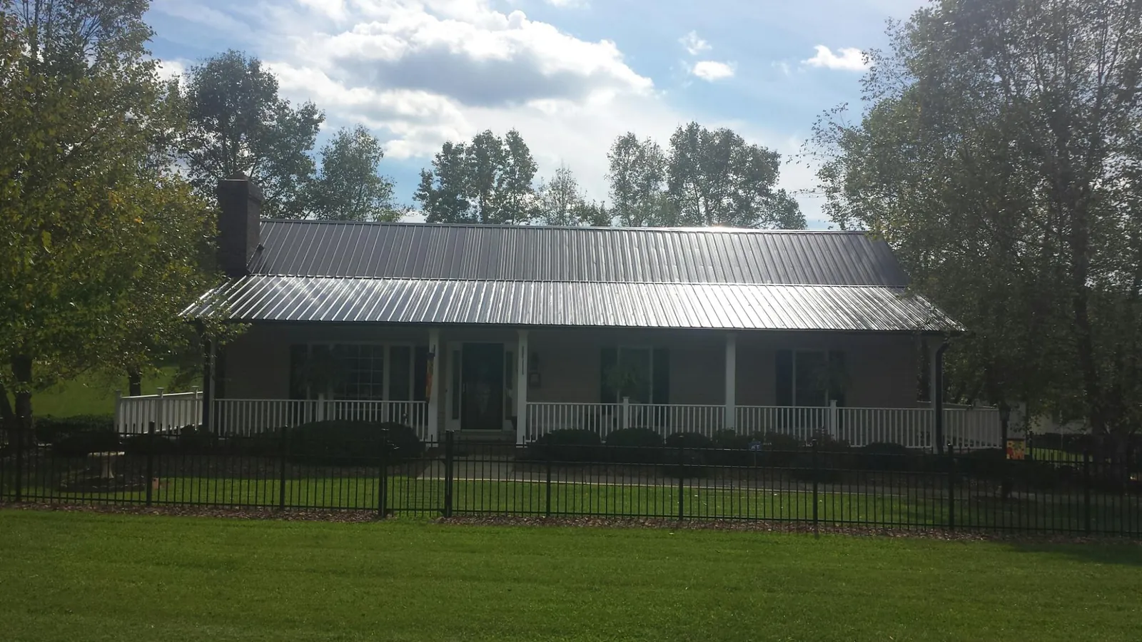 Gray metal roof on a brick ranch with a full width front porch — Gutter Guard Installation work by our crew in Fort Calhoun