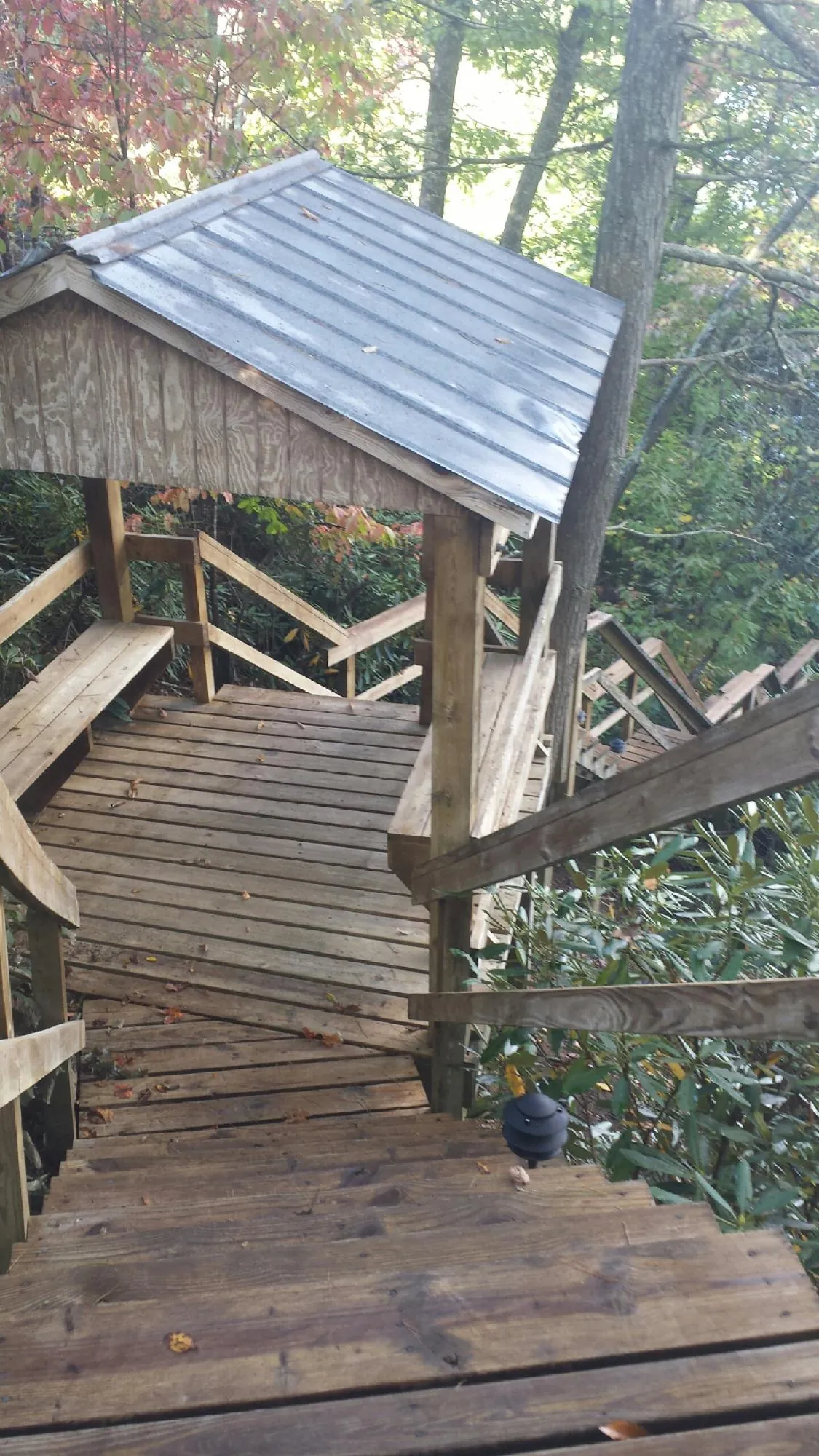 Metal roofed shelter over wooden steps on a wooded walkway — Skylight Repair & Installation work by our crew in Fort Calhoun
