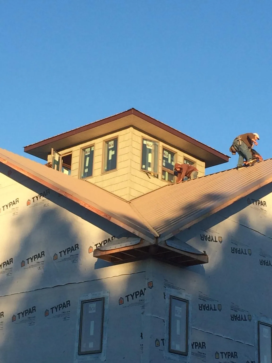 Roofers working around a rooftop cupola on a new metal roof at sunset — Roof Waterproofing in Fort Calhoun by Roofing Brothers